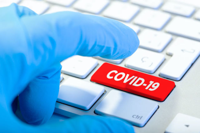 Hand with protecting glove and Keyboard with red key and COVID-19 message. Coronavirus concept